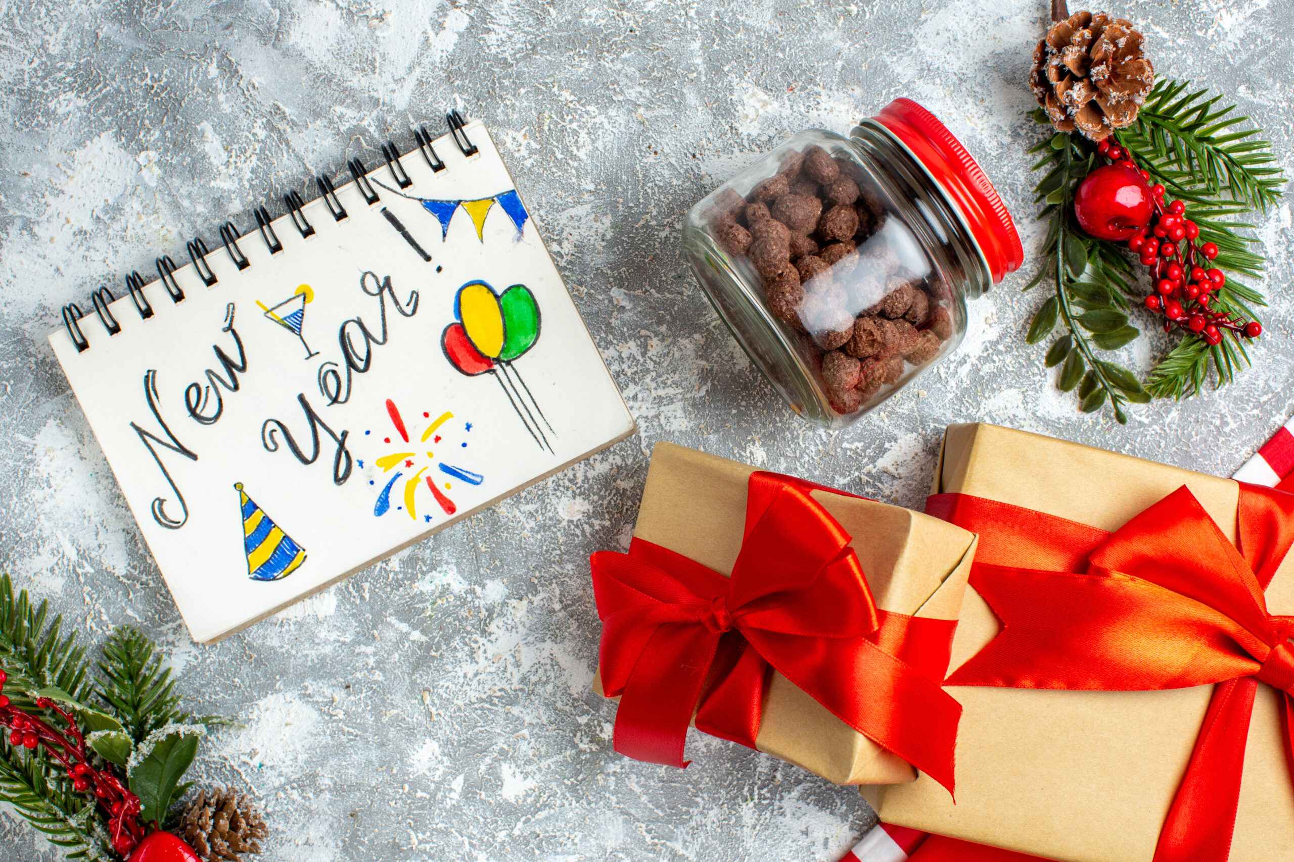 top-view-new-year-written-notebook-xmas-gifts-cereal-jar-grey-table